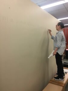 A person standing on a bench and writing on a wall.