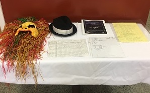 A table with a mask, hat, and various documents displayed.