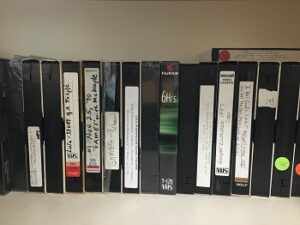 A row of vertical video tapes with handwritten labels