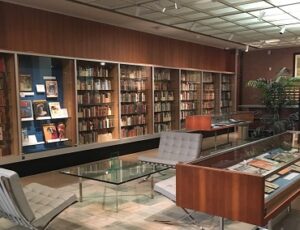 A library lobby with bookshelves, armchairs, and display cases.