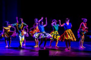 Eight dancers in colorful costumes on stage
