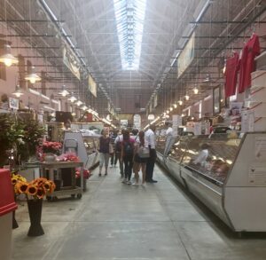 A view of an indoor market, with flowers and deli cases