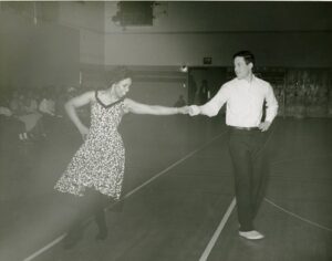 A man and a woman dance together with linked hands.