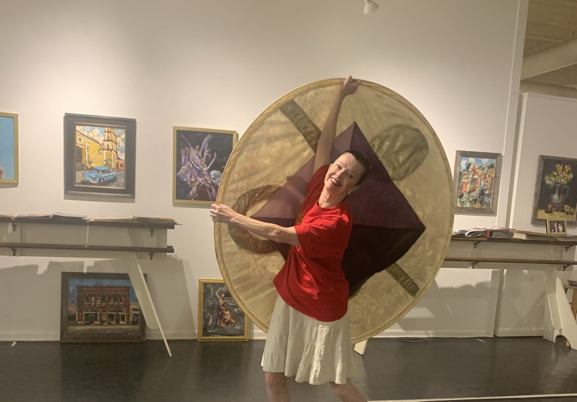 A woman in a red shirt dances holding a disc of fabric