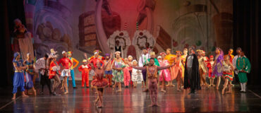 A Black ballet company onstage. Two dancers bowing in front of the rest.