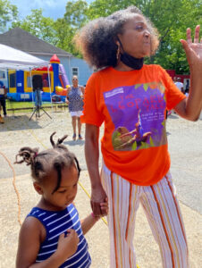 A woman holds a little girl's hand.