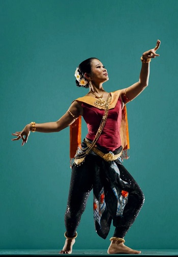 Full-body shot of a Cambodian dancer against an aquamarine background.