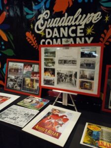 A display of photographs and illustrations in front of a black wall painted with the company's name.