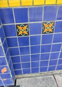 A blue and yellow tile wall with two decorative tiles.