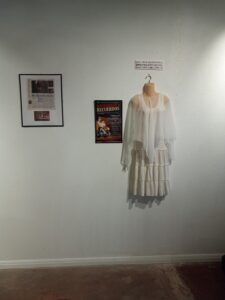 A white top and skirt and two framed posters hanging on a white wall.