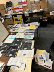 A collection of playbills spread out on a long table.