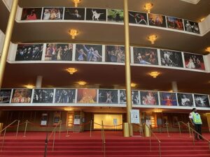 A view of photographs displayed in an opera house lobby.