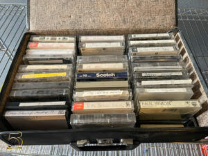 An open suitcase with rows of tapes inside