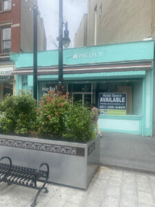 A green building with "RETAIL SPACE AVAILABLE" on a sign in the window