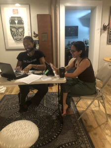 Two people sitting at a table with iPads and laptops smiling.