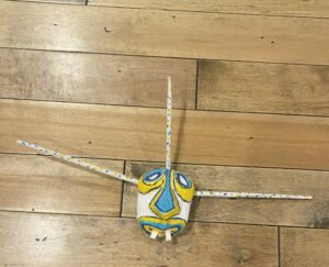 A colorful mask with long spokes coming out of it