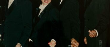 Three men and one woman in dress clothes smiling