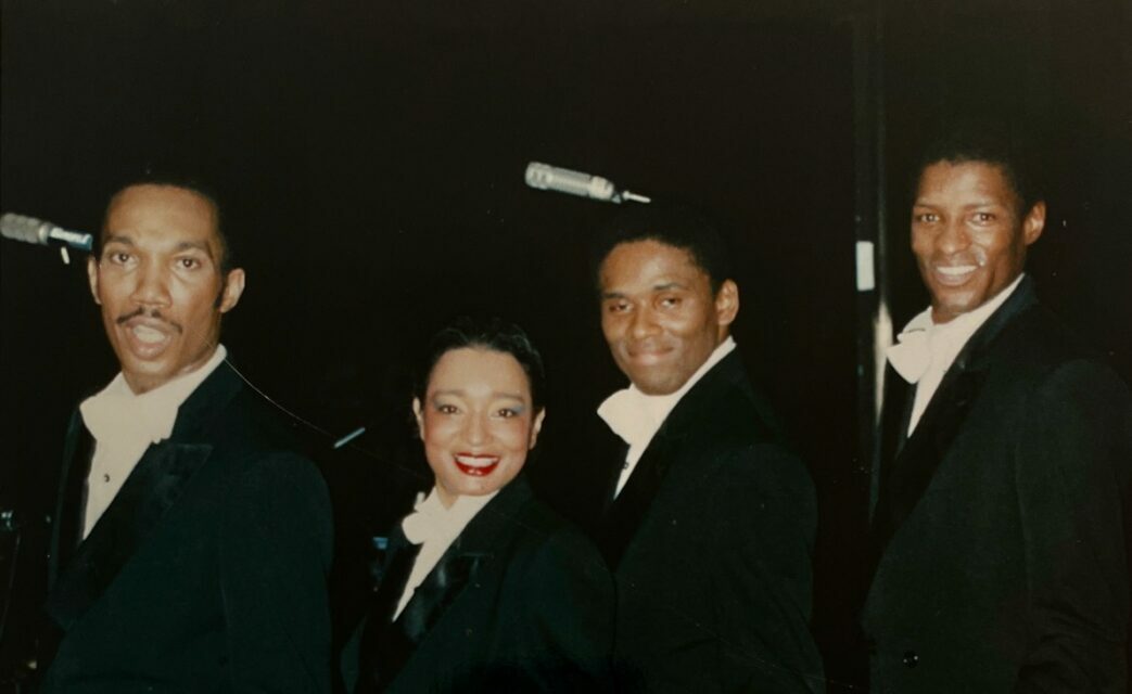 Three men and one woman in dress clothes smiling
