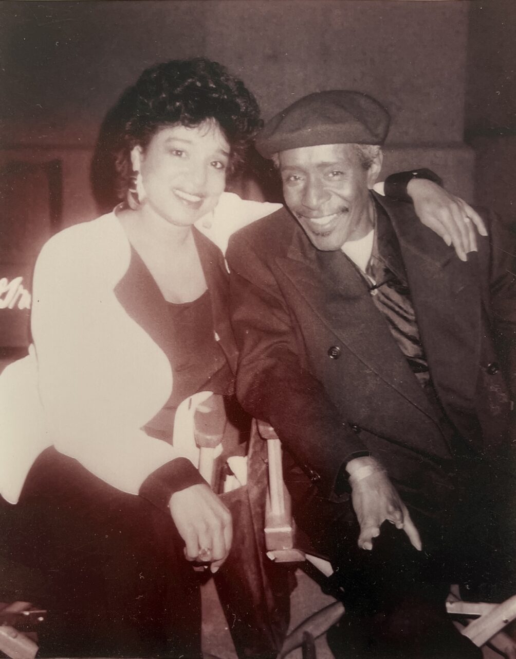 Two people smiling and posing with their arms around each other.