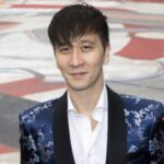 Biracial White/Asian American man wearing a white button down shirt and blue and silver silk Chinese tuxedo jacket. Photo by Eli Schmidt.